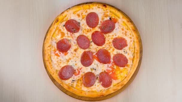 Masada ahşap tahta üzerinde salamlı pizza. Yakın çekim Üstten Görünüm. — Stok video