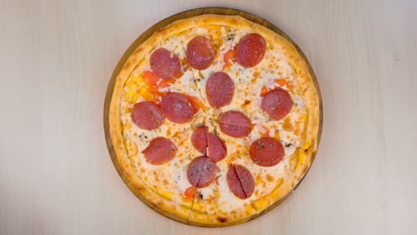 Skivning salami pizza på träskiva på bordet. Närbild ovanifrån. — Stockvideo