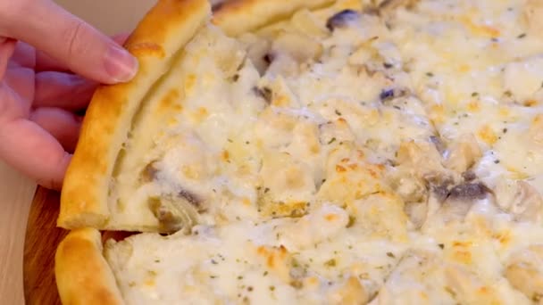 Člověk bere pizzu se žampiony žampiony a sýrem na dřevěné desce na stole. Detail ruční. — Stock video