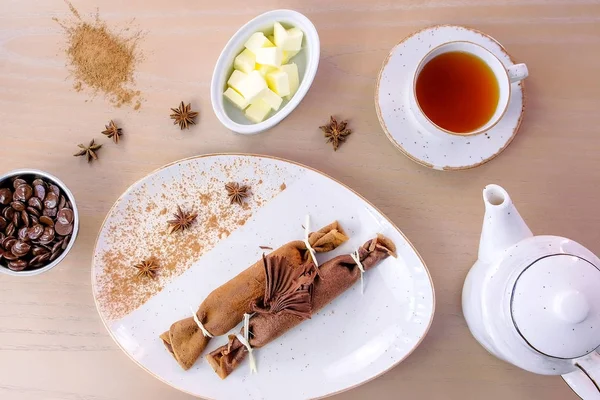 Rosyjski Czekoladowe naleśniki, blini z twarogiem na talerzu. Podawane z filiżanką herbaty i czekolady. Widok z góry. — Zdjęcie stockowe