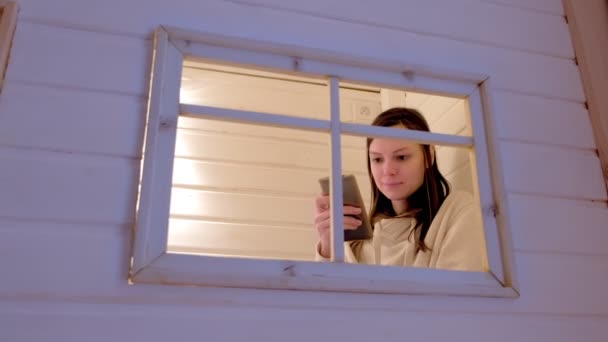 Woman types a message on phone sitting in kids play house, mom hiding from children. — Stock Video