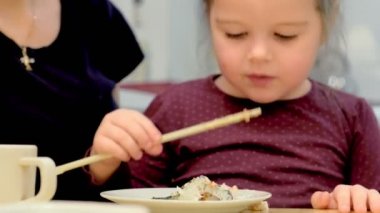 Annesi tarafından rulo ile beslenen küçük bir kız portresi.