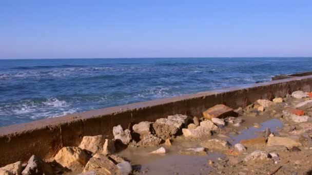 Бризки води з бурхливої хвиль на breakwater на набережній, буря моря, хвилі і гуркотом об скелі під Синє небо. — стокове відео