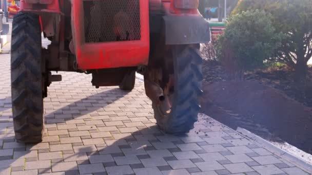 Traktor på trottoaren i staden, gas från avgasröret. — Stockvideo