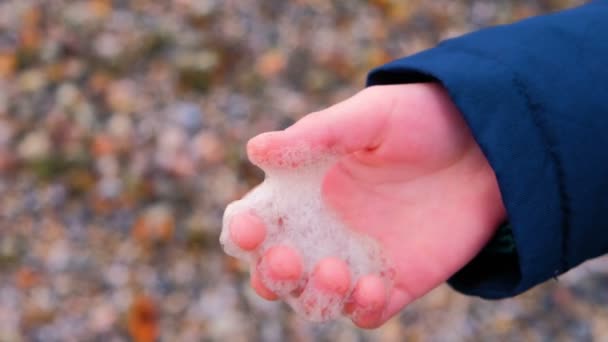 Schuim van de zee in jongens hand. Winter aan de kust. — Stockvideo