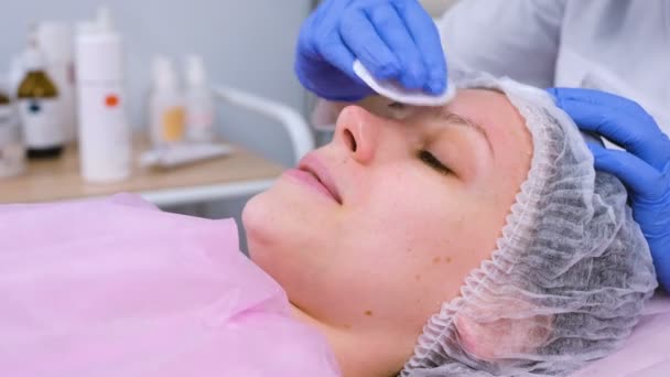 Esteticista lava la cara de las mujeres utilizando almohadillas de algodón de la máscara. Cara de limpieza . — Vídeos de Stock