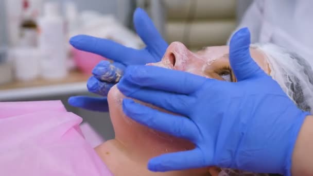 Schoonheidsspecialiste verwijdert en rolt een masker van dames gezicht. Reinigen van gezicht. Gezicht close-up. — Stockvideo