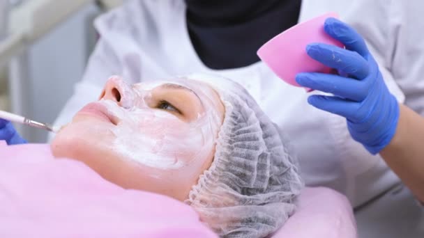 Cosmetologist βάζει μάσκα στο γυναικείο πρόσωπο με βούρτσα. Ενυδάτωση προσώπου. Face close-up. — Αρχείο Βίντεο