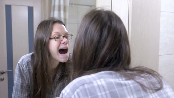 Mulher olhando em seus dentes no banheiro perto do espelho e bocejo . — Vídeo de Stock