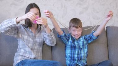 Mutlu anne ve oğlu kanepede oturan balçık ile oynarken.