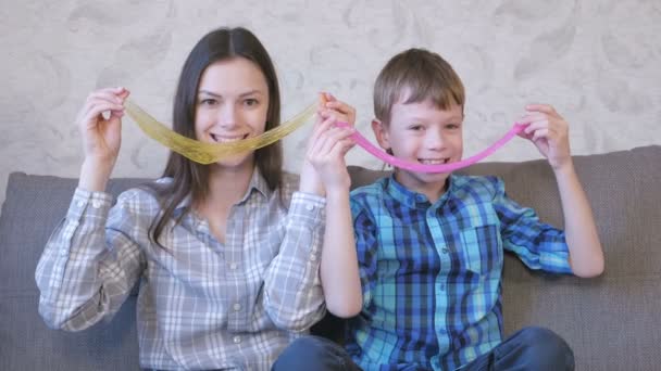 Glad mamma och son spelar med slem som sitter på soffan. Stretching slem. — Stockvideo