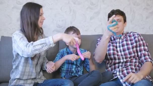 Feliz familia mamá, hijo y papá y jugando con los slimes sentados en el sofá. Estirar el limo . — Vídeos de Stock