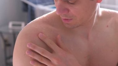 Büyük kırmızı sivilce bir omuz yakından görmek mans. Adam el ile bir sivilce sıkarak.