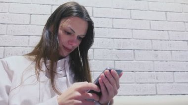 Kadın cep telefonuna oturan ve kafede birini bekleyen bir mesaj yazıyor. Yan görünüm.