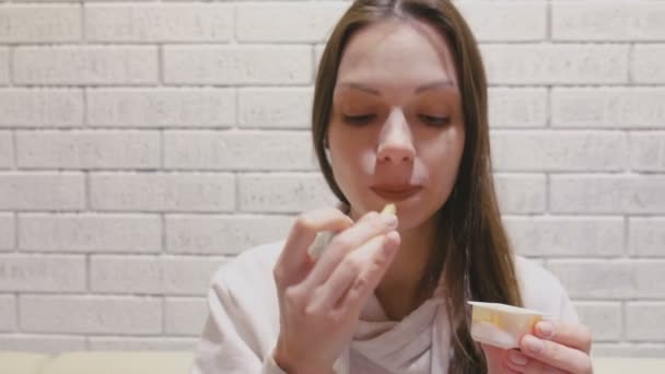 Жінка їсть фрі з сирним соусом у кафе. — стокове відео