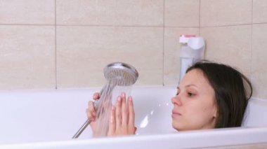 Kadın banyo yapıyor. Kötü bir günden sonra rahatlayın. Elle bir suya dokunma.