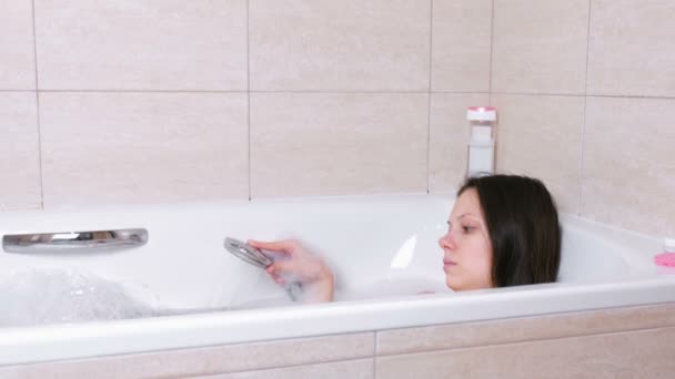 Woman is taking a bath with foam. She pours her body water from the shower. — Stock Video