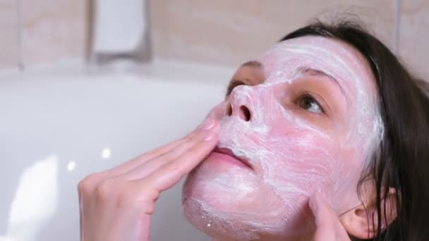 Belle femme brune met un masque sur le visage couché dans la salle de bain à la maison. Gros plan sur le visage . — Video