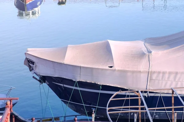 Boat covered with tarpaulin in the seaport is parked on the water. — Stock Photo, Image