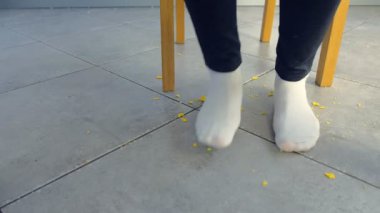 Kadın masaya kadar alır ve masanın altındaki kırıntıları üzerinde adımlar, ayaklarını sallıyor. Ayaklar yakın çekim.