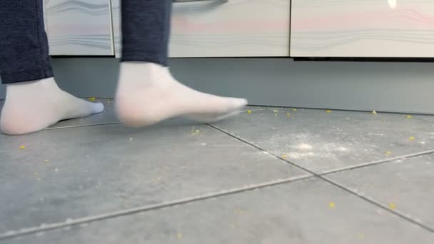 Kvinnan går på det smutsiga golvet i köket. Matrester och smulor på köks golvet. Ben närbild. — Stockvideo