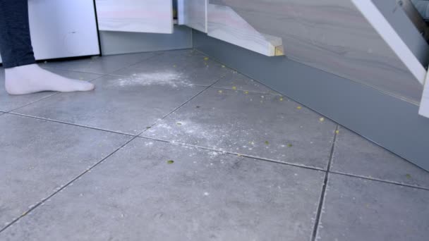 Woman cooks standing on the dirty floor in the kitchen. Leftovers and crumbs on the kitchen floor. Legs in white socks close-up. — Stock Video