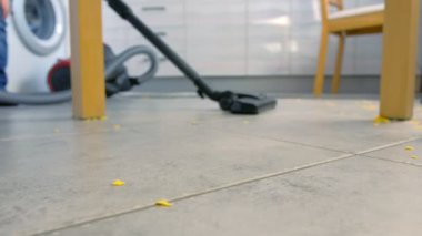 Çocuk mutfak zemini süpürme. O gri çini dağılmış Mısır gevreği kadar tidies. Bacaklar yakın çekim.