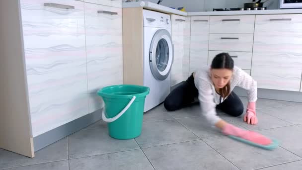 Pembe kauçuk eldiven kadın mutfak zemin bir bez ile yıkıyor. Katta gri fayans. — Stok video