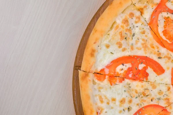 Pizza mit Tomaten und Käse auf Holzbrett vierteln. Ansicht von oben. — Stockfoto