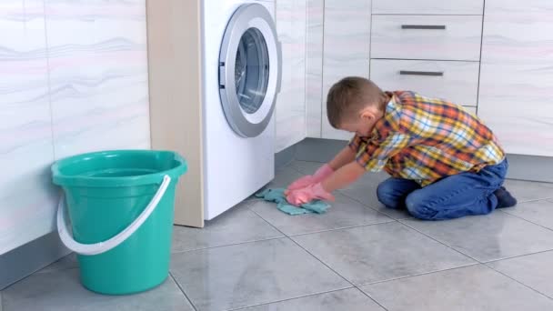 戴橡胶手套的男孩在厨房里洗地板。儿童家庭职责. — 图库视频影像