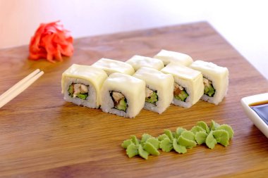 Tavuk, salatalık, yeşil ve krem chesse rulo üstte ahşap tahta sebze ile servis.