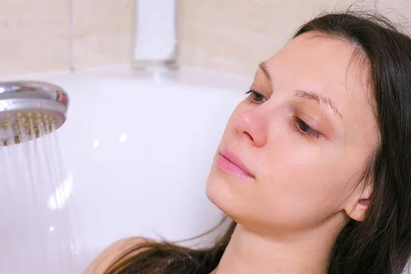 Woman is taking a bath. She pours her body water from the shower. Close-up face. — Stock Photo, Image