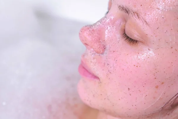 Schrobben op dames gezicht met nauwe ogen. Gezicht close-up. Vrouw ia nemen van een bad met ogen dicht. — Stockfoto