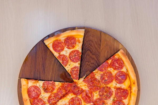 Slicing salami pizza on wooden board on the table. Close-up side view. — Stock Photo, Image