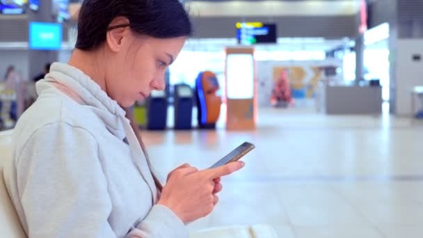 Online-Registrierung der Frau auf ihrem Handy in der Flughafenhalle, Seitenansicht. — Stockvideo