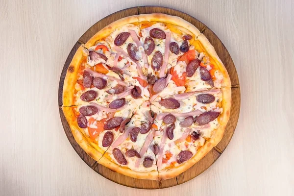 Pizza mit Räucherwurst, Schinken und Käse in Scheiben schneiden. Nahaufnahme. — Stockfoto