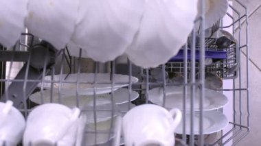 Adam bulaşık makinesi kirli beyaz yemekler yükler ve sepet içinde iter.