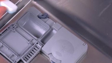 Mans el bulaşık makinesi otomatik bölmesine deterjan tablet koyarak.