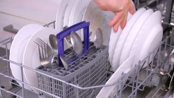 Die Hand des Mannes stellt einen weißen, schmutzigen Teller in die Spülmaschine und lässt ihn in der Küche laufen.. — Stockvideo