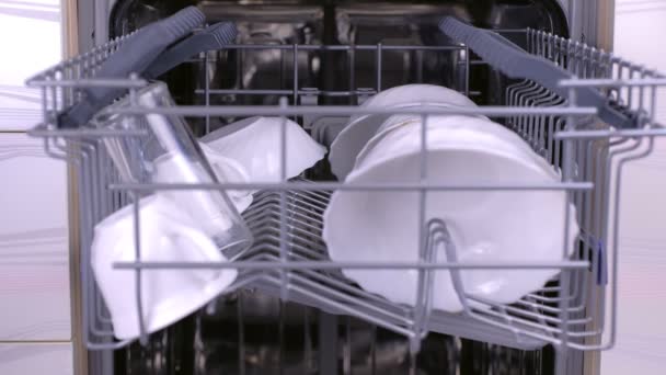 Man is putting a cups in the dishwasher, pushing the basket inside and runnig dishwasher. — Stock Video