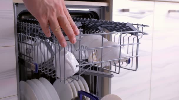 La mano de hombre está empujando las cestas y cerrando el lavavajillas con platos blancos sucios . — Vídeos de Stock