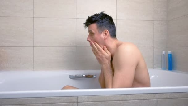 Man is het wassen van zijn gezicht zitten in Bad. — Stockvideo