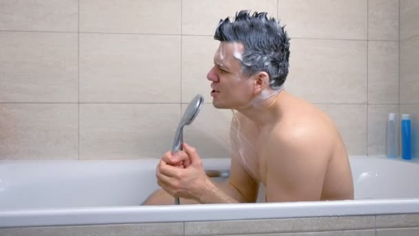 Man with Mohawk shampoo hairs is singing while he is washing in bathtub. — Stock Video