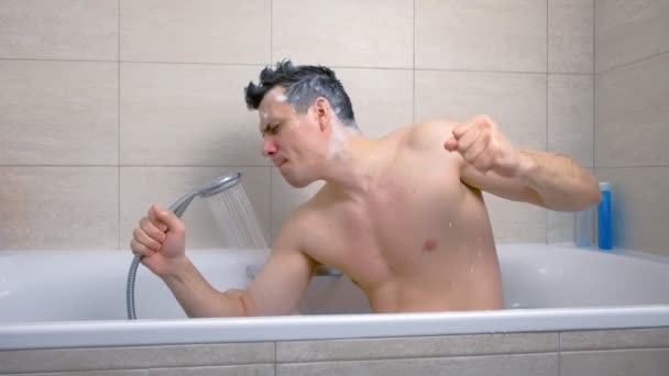 モホークシャンプーの髪を持つ男は、彼が浴槽で洗っている間、熱意を持って歌っています. — ストック動画