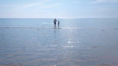 Baba ve oğul deniz plajında oyuncak motorlu tekne başlatmak.