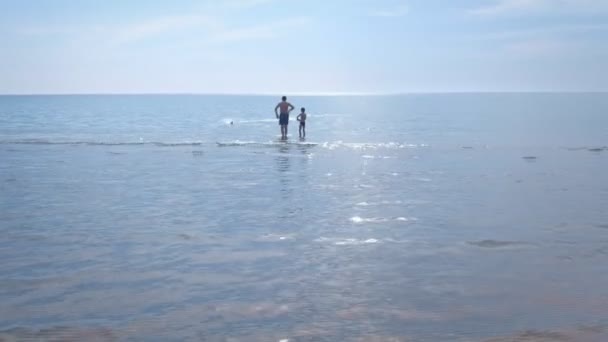 Papà e figlio avviano la barca a motore giocattolo sulla spiaggia del mare . — Video Stock