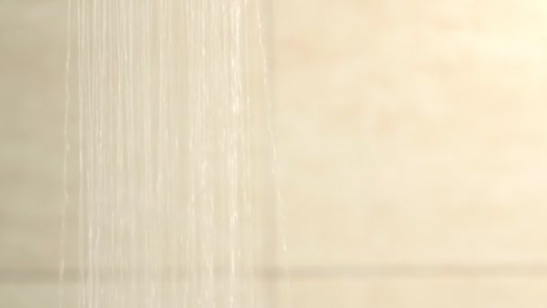 Nalévání vody ze sprchy proti béžové stěně. — Stock video