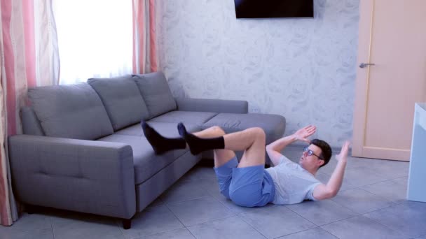 Nerd man doet abdominale crunches oefening leggen op de vloer ademen in en uit thuis. Sport humor concept. — Stockvideo