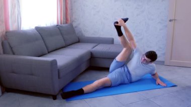 Çılgın adam evde minyon üzerinde yatan bacaklarını germek için çalışıyor. Spor mizah konsepti.
