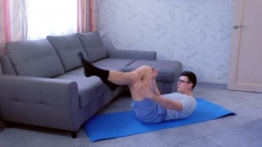 Nerd adam evde mat üzerinde döşeme dinamik karın crunches egzersizleri yapıyor. Spor mizah konsepti.